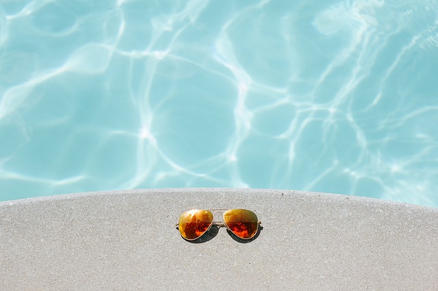 sluneční brýle na okraji bazénu
